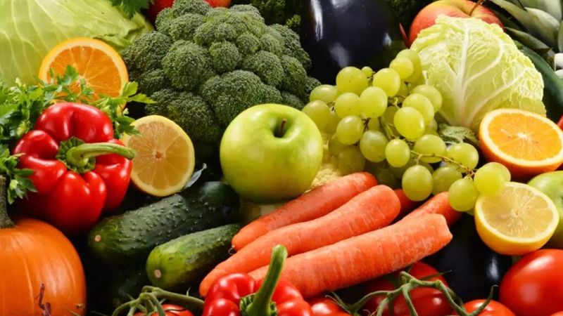 A selection of fresh fruit and vegetables including carrots, broccoli, red peppers, apples, grapes and tomatoes 