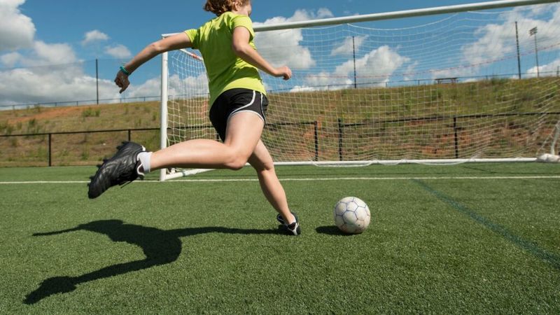 Girl kicking football into goal 