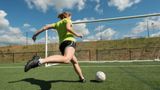 Girl kicking football into goal 