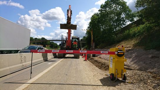 Digger being stopped on a motorway work site by a solar-powered barrier