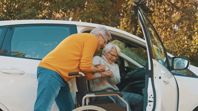 Older man helps disabled woman out of car
