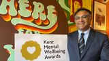 Dr Anjan Ghosh with a sign promoting the Kent Mental Wellbeing Awards at the Revival Cafe,  Whitstable