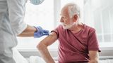 Nurse gives older man an injection in his arm