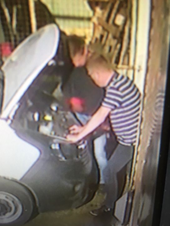 Two individuals work under the bonnet of a white van