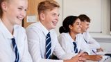 Four secondary school children in uniform smiling in class