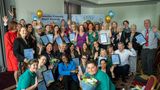 A group of people, some holding certificates and balloons, at the Dementia Friendly Kent Awards, gathered around banners and smiling for the camera