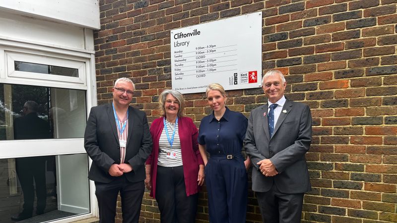 Four people stand in front of a sign which says Cliftonville Library.
