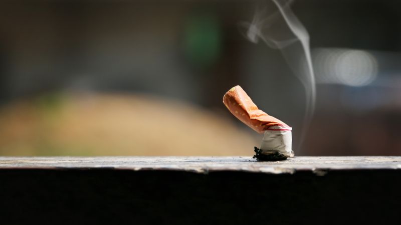 A smouldering cigarette butt on a wooden floor