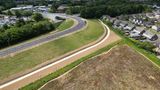 A drone image of houses on the right, grass and to the left a road.