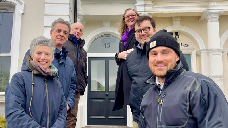 A group of six officers and members from Kent County Council and Folkestone and Hythe District Council stand on the front steps of 45 Augusta Gardens in Folkestone with the developer after its refurbishment