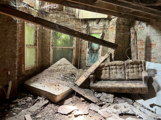 A derelict room in an old building in Folkestone showing a ceiling coming down and an old sofa