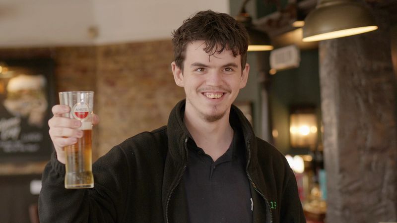 Archie, a Grow19 student, holding up a pint in the pub he worked at