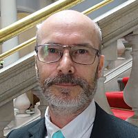 Jamie Henderson is smiling for his headshot photo in front of the county hall steps