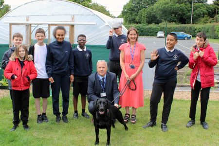 Pupils in uniform standing in the garden at Broomhill Bank School with teachers, including Executive Headteacher Steve Ackerley, and a black dog. 