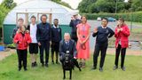 Pupils in uniform standing in the garden at Broomhill Bank School with teachers, including Executive Headteacher Steve Ackerley, and a black dog. 