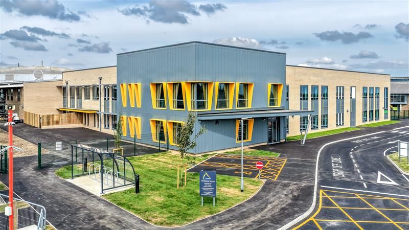 A landscape image the new building at The Beacon School in Walmer with yellow window frames, a bike shelter out the front and the new school sign