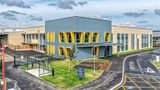 A landscape image the new building at The Beacon School in Walmer with yellow window frames, a bike shelter out the front and the new school sign