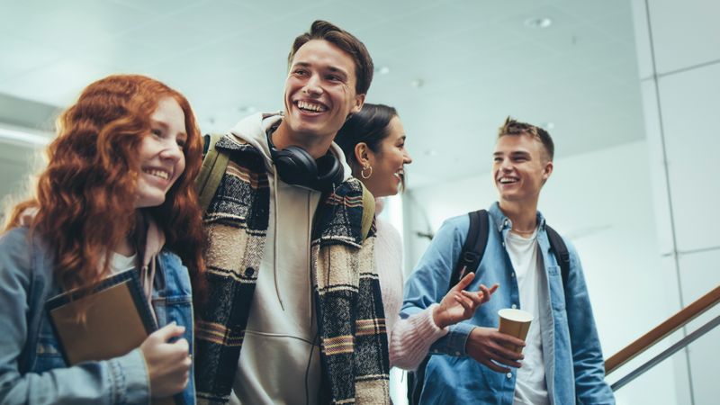Four students talking and laughing as the walk upstairs  