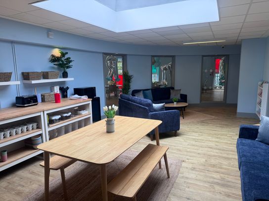 a kitchen and living room area with a wooden table and navy sofas
