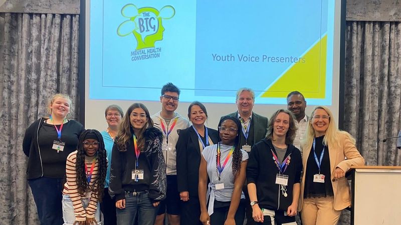 A group of young people and adults in front of a sign saying Big Mental Health Conversation