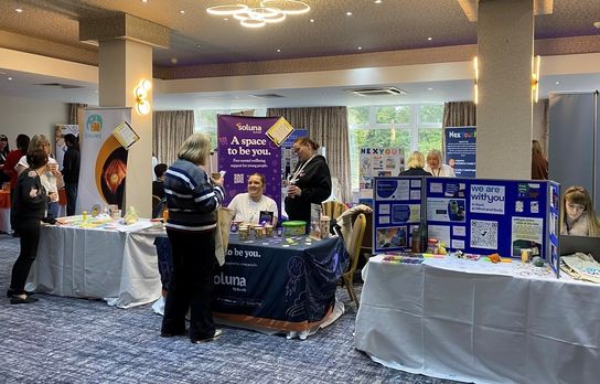 A number of stalls in a hall with signs about mental health support