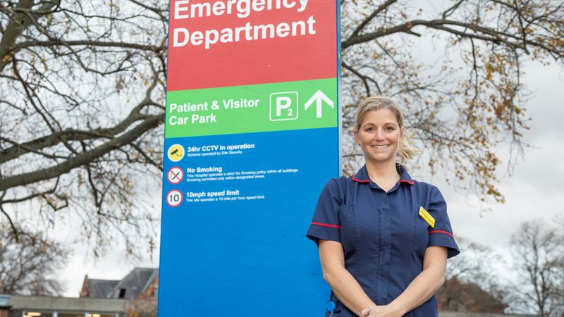 Nurse standing outside by hospital sign