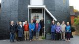 A group of men and women standing outside Cranbrook Windmill smiling at the camera.