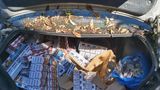 An open car boot showing hundreds of seized cigarettes in boxes