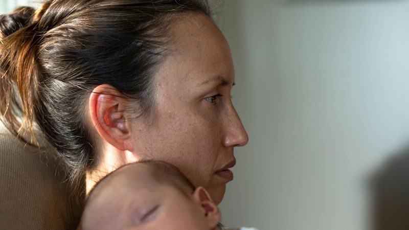 Woman holding young sleeping baby