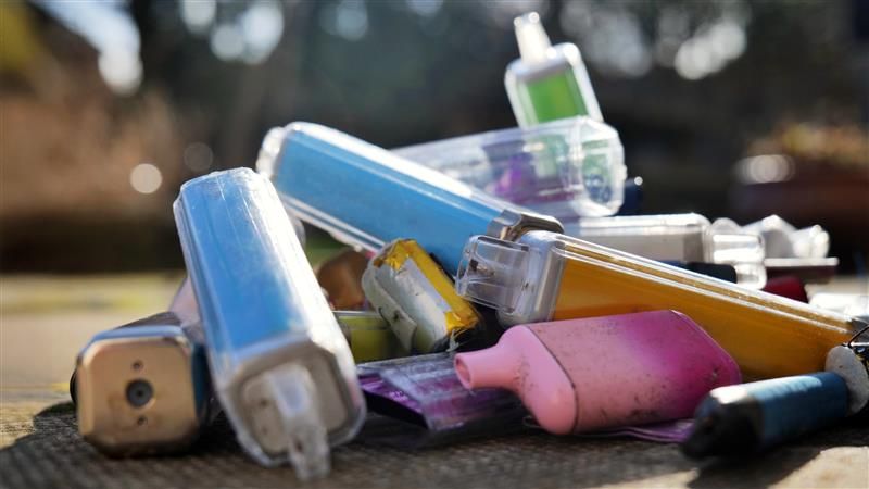 A pile of colourful used disposable vapes on the ground
