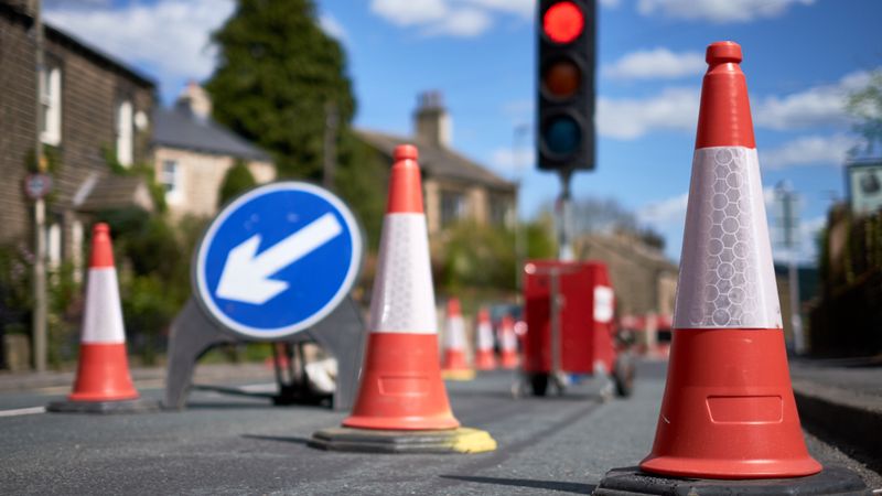 A red signal on a traffic light behind a series of road cones marking out roadworks 