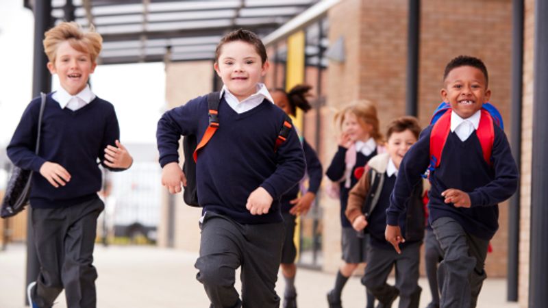 Primary school children in uniform running out of school