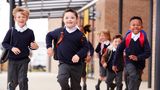 Primary school children in uniform running out of school
