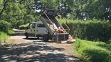 A photo of a truck on a country road fly-tipping lots of waste onto the road.