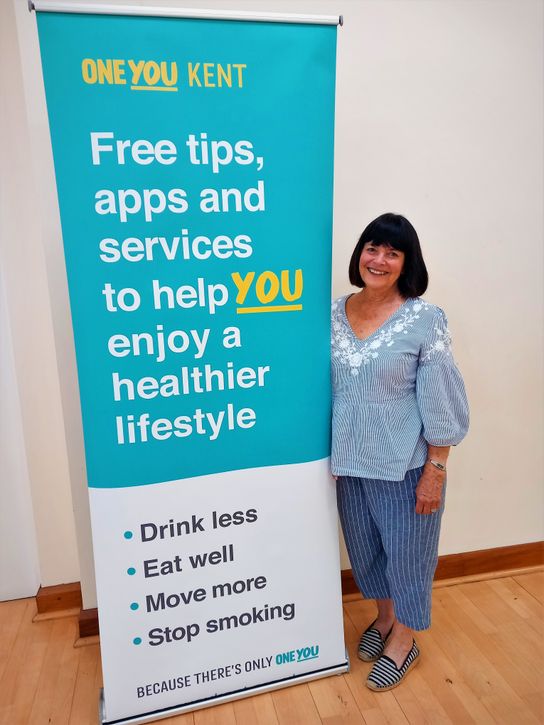 Sue beside a One You Kent banner 