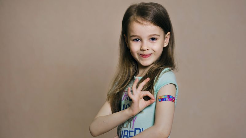 Young girl with brightly coloured plaster on her arm