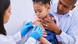 Doctor puts plaster on young girl's arm following vaccination