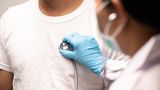 A doctor holds a stethoscope against a man's chest to check his heart health