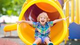 Child on yellow slide in outdoor play area