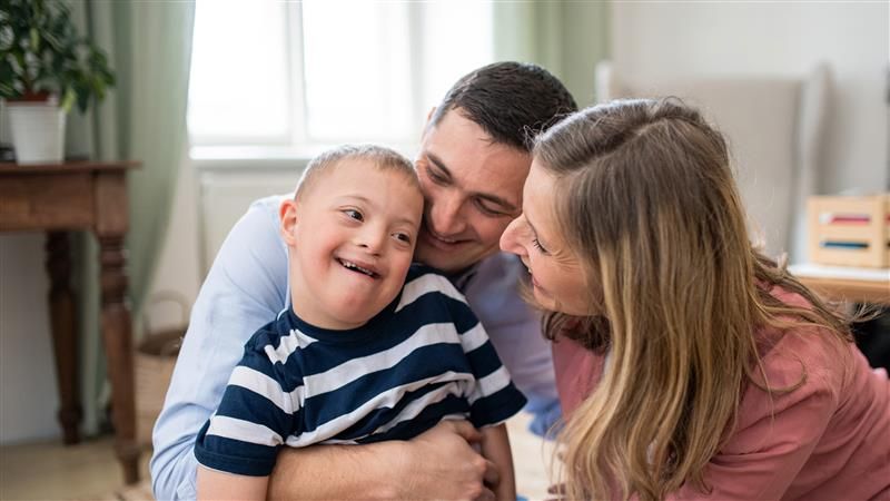 A mother and father cuddling and smiling at their young son who has SEND 
