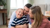 A mother and father cuddling and smiling at their young son who has SEND 