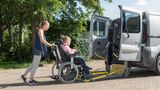 A child in a wheelchair being helped into a the back of a taxi by her mum to be taken to school