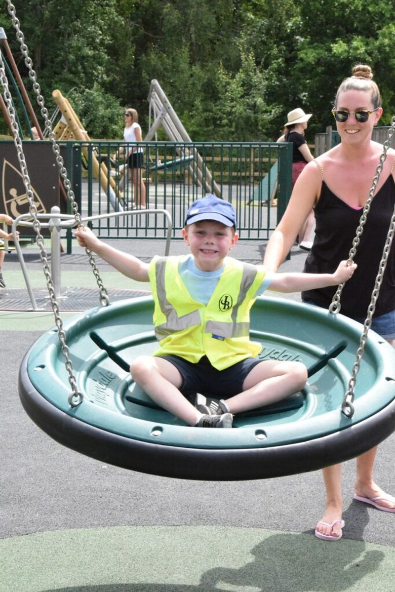 Country Parks child visitor swinging on swing