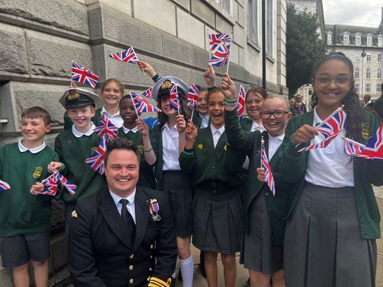 Children wave flags at County Hall to welcome HMS Kent's crew