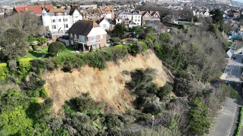 Drone photo of the Road of Remembrance showing the landslip. The area is surrounded by trees and houses can be seen on the top of the cliff.