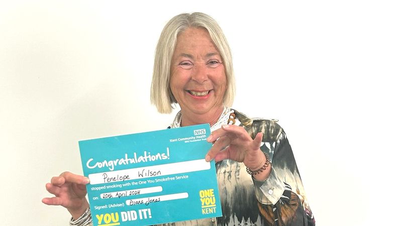 A smiling Penny Wilson holds up her 'Congratulations' card for quitting smoking from One You Kent