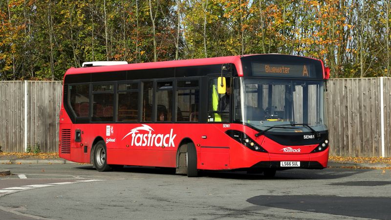 A red bus drives around a road.