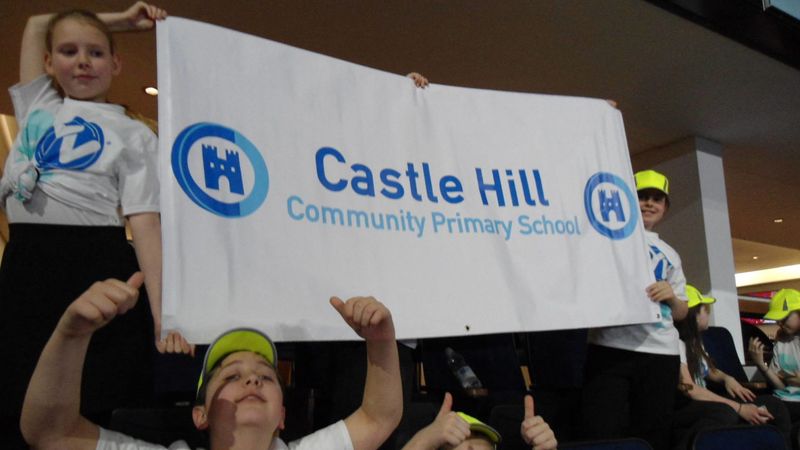 A group of children are holding a sign that says Castle Hill Community Primary School.