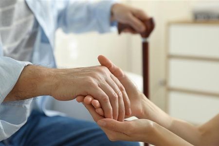 Carer holding elderly person's hand