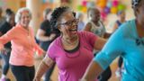 Woman in pink t-shirt laughing as she enjoys a zumba class